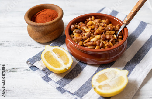 Prebranac. Balkan baked beans. Serbian, Montenegrin, Bosnian, Croatian, Slovenian cuisine. Uncooked beans, onion, lemon, paprika powder. White wooden background. Close up. Space for text photo