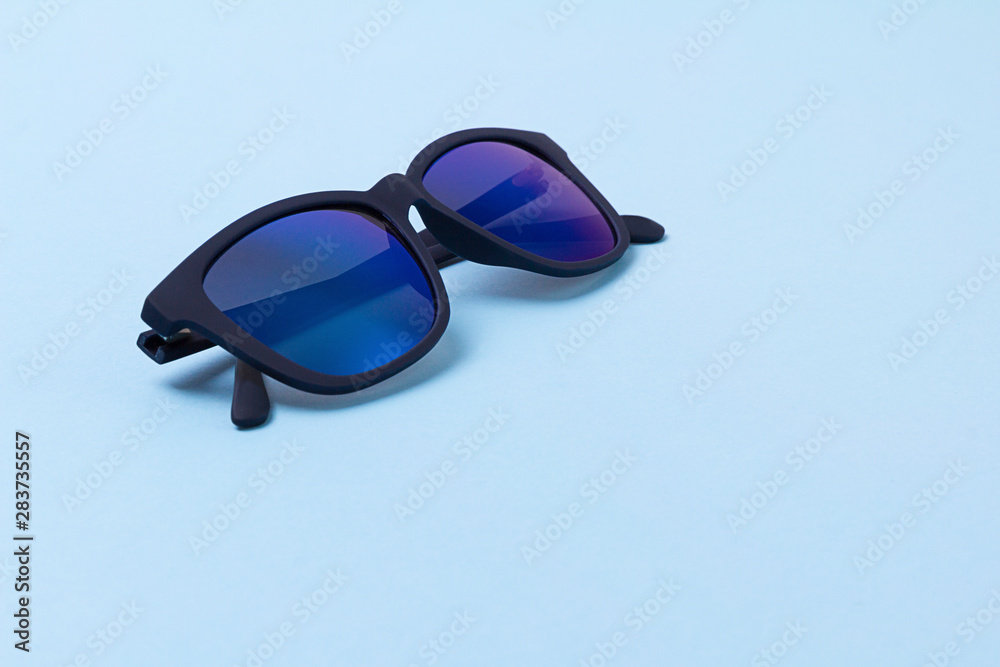 Men's trendy modern sunglasses on blue background.