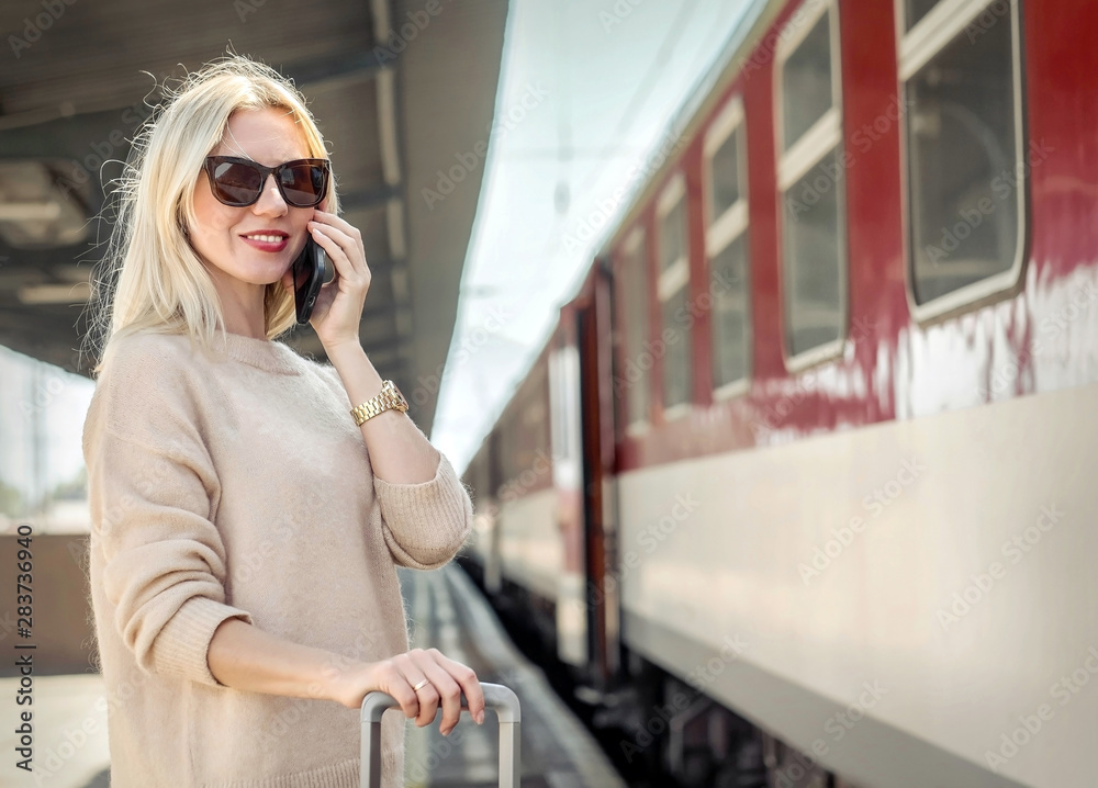 Blonde woman with her luggage stay  and speak in her mobile near