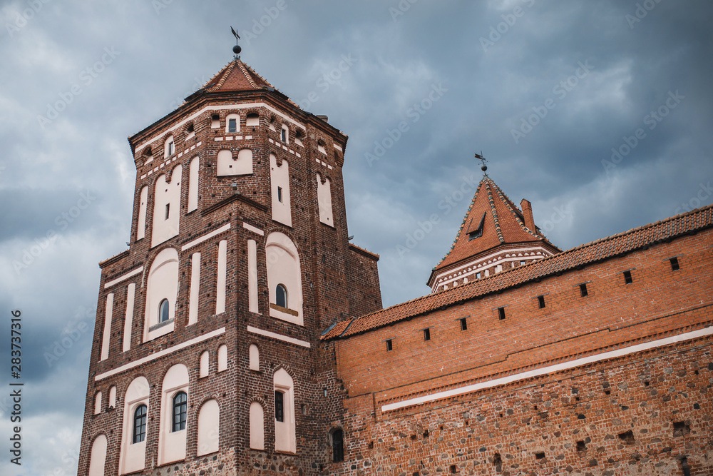 Square tower and massive impregnable walls of an old medieval red brick castle