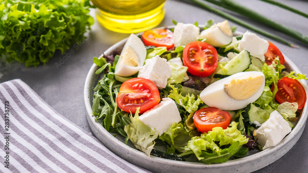 Eggs, tomatoes, cheese and mixed greens on a plate. Healthy salad  with copy space.