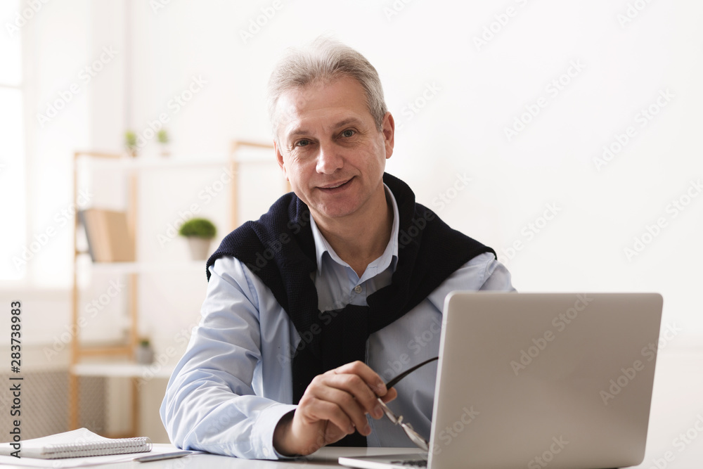 Trendy mature man working on laptop at home Trendy mature man working on laptop at home