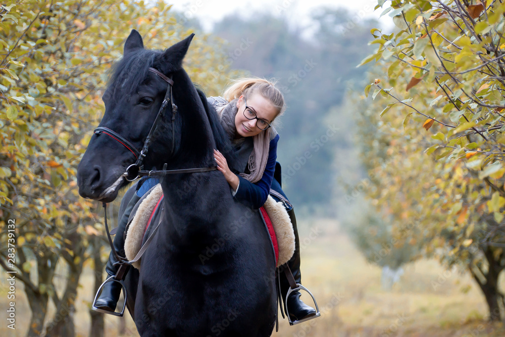 Obraz premium A young, beautiful girl on a walk with a horse in early autumn walks in the park.
