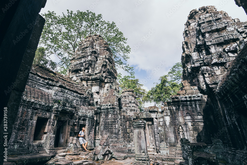 Caucasian man with camera standing among the ruins of Angkor Wat temple complex in Siem Reap, Cambodia