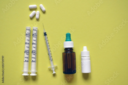  container for medical drops, syringes and pills on a yellow background