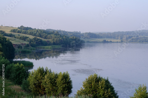 nature on the banks of the river green bushes and trees in the early summer morning at dawn in silence and tranquility