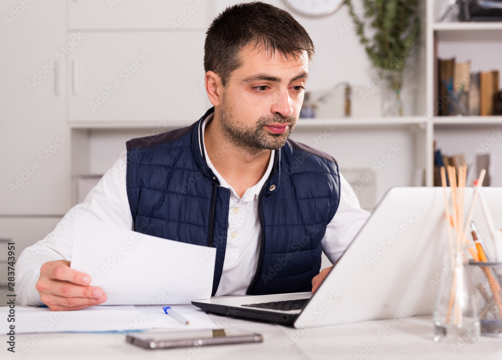 Naklejka premium Businessman in shirt working with laptopt and documents