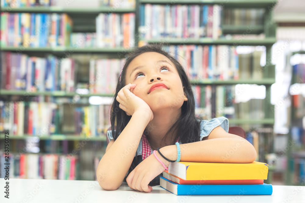 Kids asian beautiful girl reading books and thinking for education and go to school in library. Education and Lifestyle Concept. Kids asian beautiful girl reading books and thinking for education and go to school in library. Education and Lifestyle Concept.