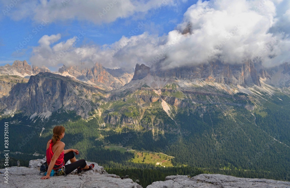 A climber is sitting on the top of Cinque Terre tower, enjoying beautiful view on Dolomites.