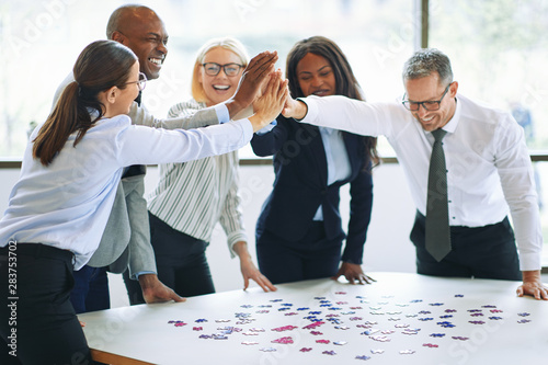 Laughing businesspeople high fiving together while solving a jig photo