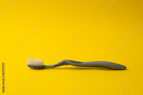 Two different grey  toothbrushes on a yellow background. All you need for teeth.