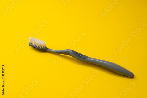 Two different grey  toothbrushes on a yellow background. All you need for teeth.