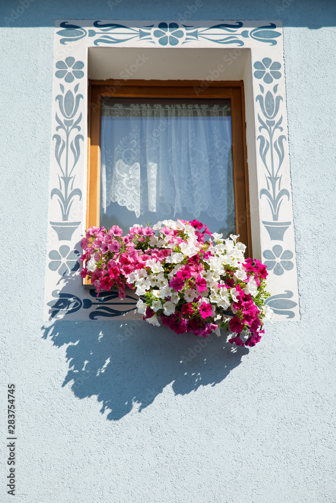 Old blue window with flowerbox full with pink flowers.