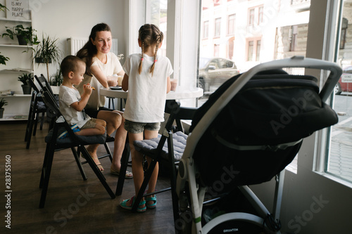 Mother with children drinking hot chocolate and latte at a local coffee shop. They are smiling and having fun. © 4Max