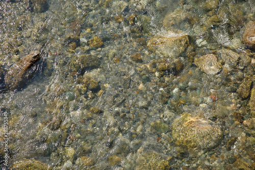 Stones in clear water of a river flowing , background.
