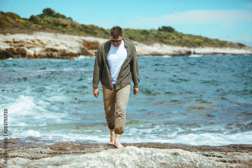 man walking by rocky beach in windy day summer vacation. enjoy sea view