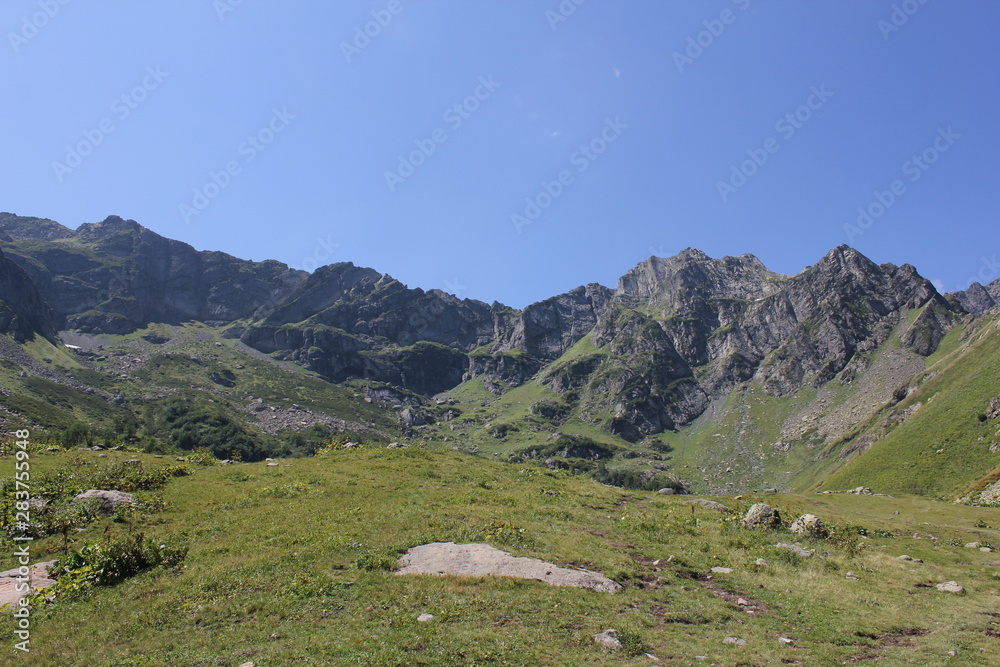 Naklejka premium Green meadows and mountains against the blue sky