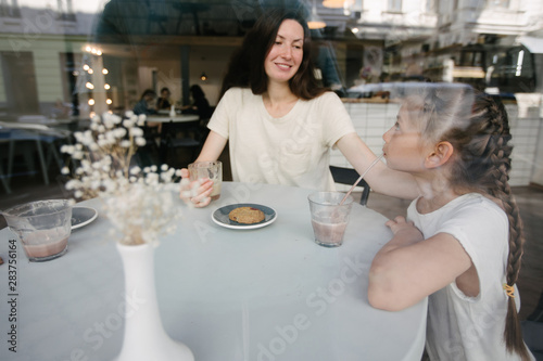 Mother with children drinking hot chocolate and latte at a local coffee shop. They are smiling and having fun.