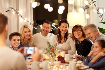 celebration, holidays and people concept - happy family having tea party and photographing by smartphone at home