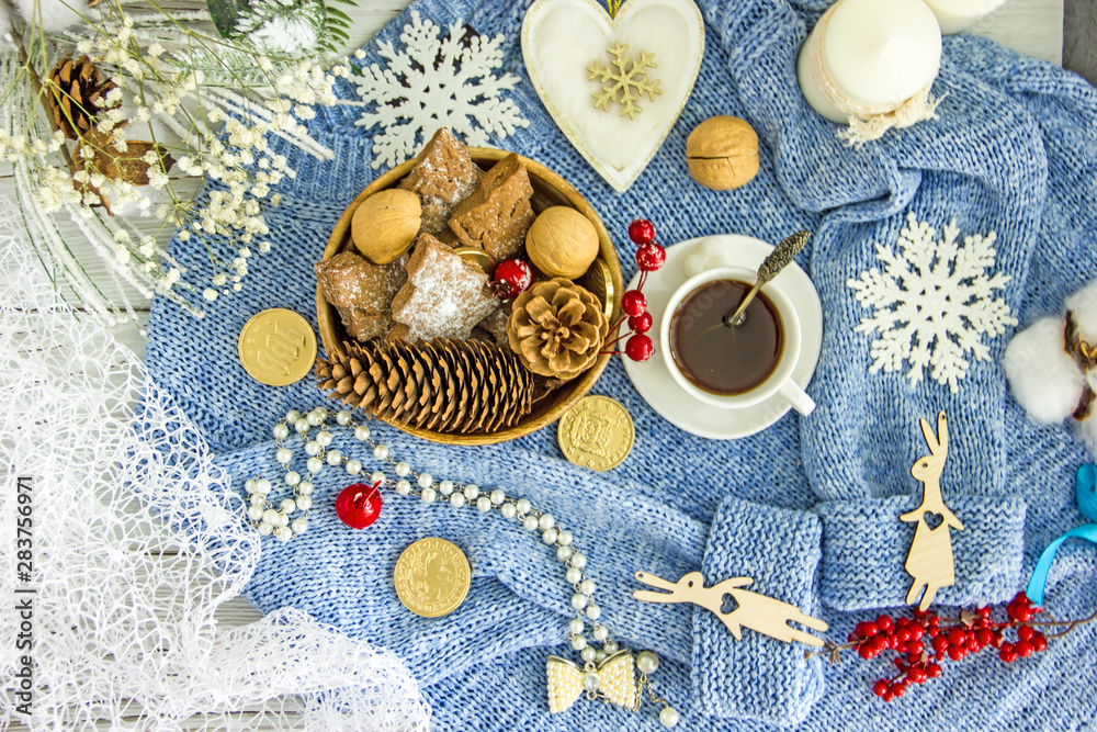 Blue knitted sweater, white cup with coffee, homemade cookies, white candles, snowflakes on a light wooden table, top view, flat lay. The concept of a New Year card, Christmas holidays. Save space Blue knitted sweater, white cup with coffee, homemade cookies, white candles, snowflakes on a light wooden table, top view, flat lay. The concept of a New Year card, Christmas holidays. Save space