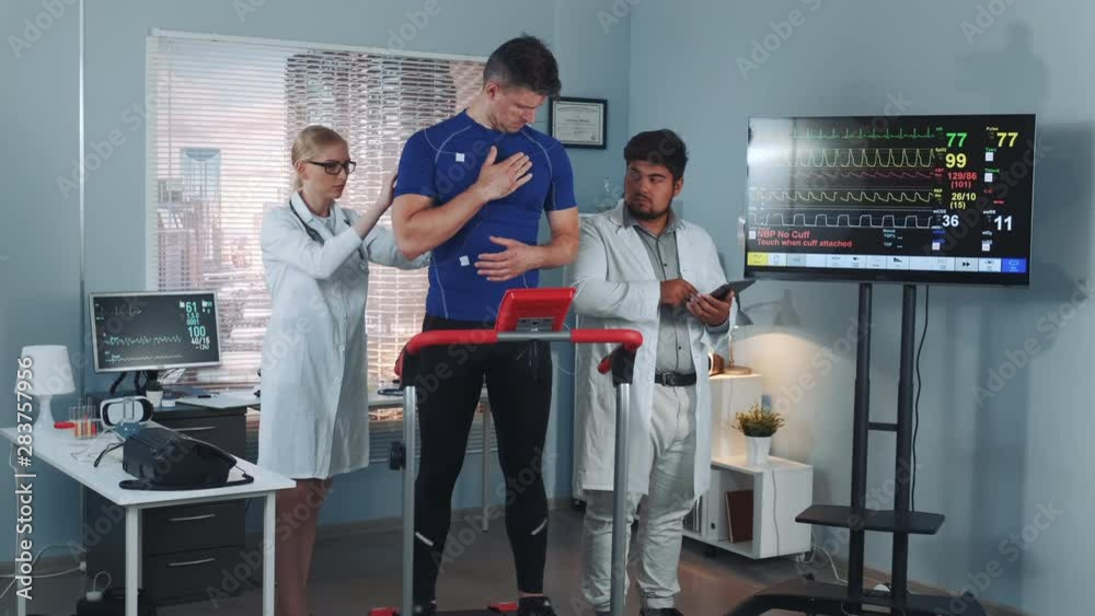 Sport medicine: woman and man doing measures on strong sportsman in modern lab with hi tech equipment. Scientific Sports Laboratory. Sport medicine: woman and man doing measures on strong sportsman in modern lab with hi tech equipment. Scientific Sports Laboratory.