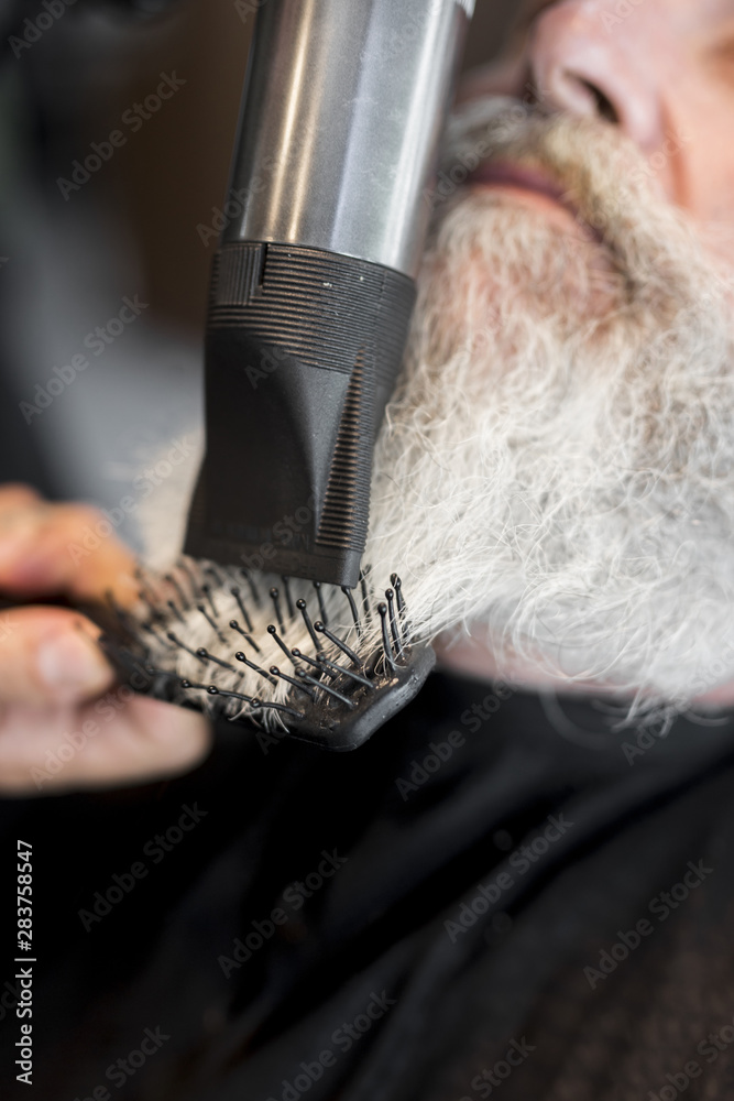 Naklejka premium Hair stylist making styling beard to client in salon