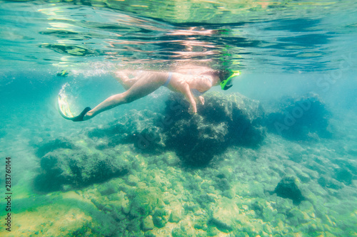 woman with snorkeling mask and flippers looking at sea bottom