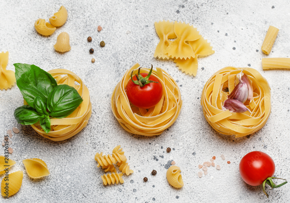 Uncooked pasta on grey stone background. Top view. Raw pasta with ingredients for cooking. Food concept. Italian food