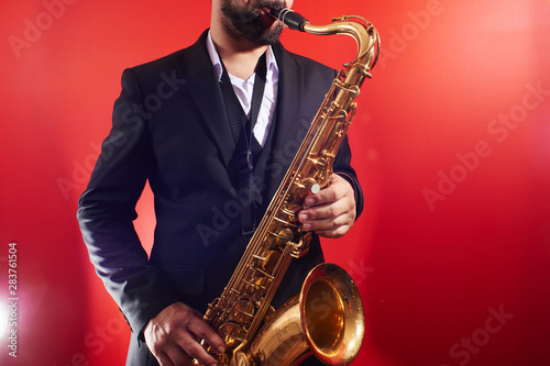 Photography Portrait of professional musician saxophonist man in  suit plays jazz music on s