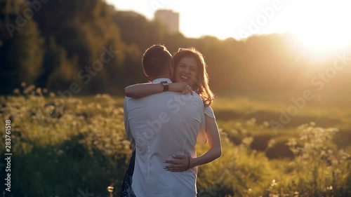 Young man and woman strolling in a meadow at sunset in summer. Romance. Summer love togetherness joy romantic memories forever together concept