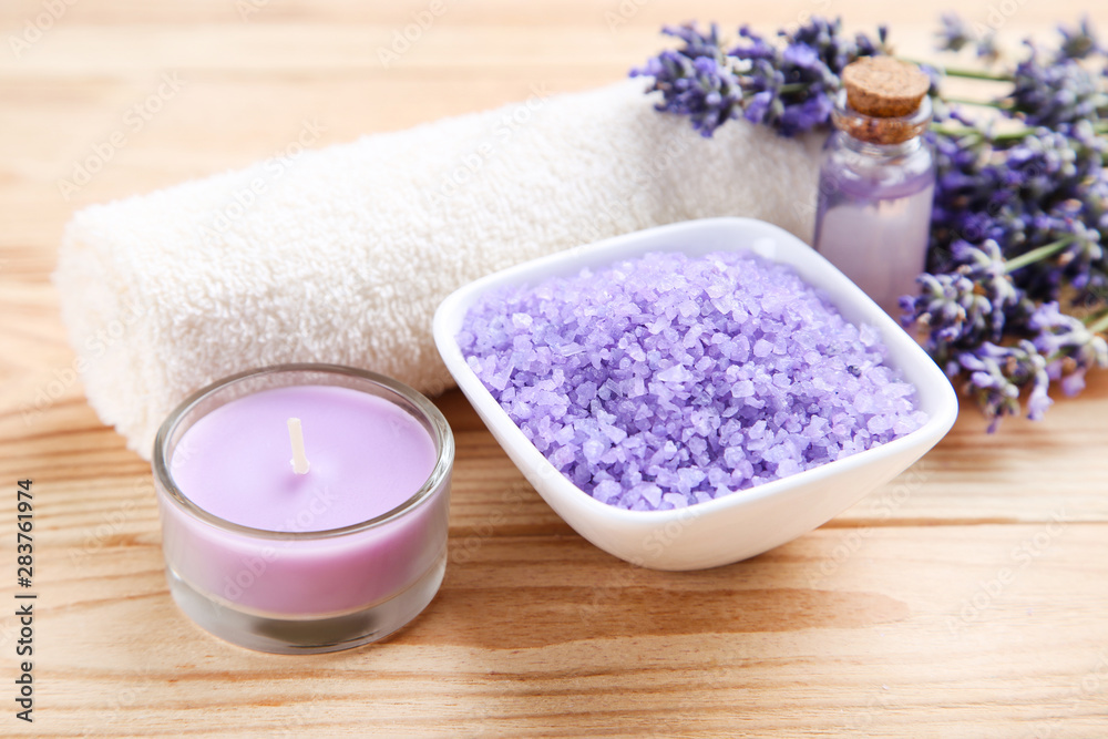 Lavender flowers with oil in bottle, salt in bowl and candle on brown wooden table Lavender flowers with oil in bottle, salt in bowl and candle on brown wooden table