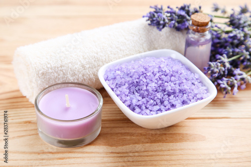 Lavender flowers with oil in bottle  salt in bowl and candle on brown wooden table