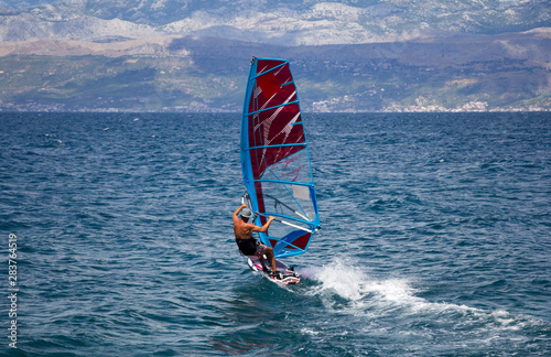 Young windsurfer in the waves in the sea