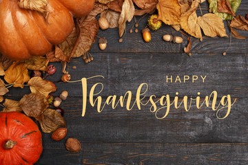 Thanksgiving Greetings. Pumpkins and dry leaves on a dark wooden background. Top view. Flat layer
