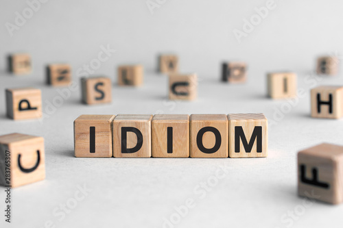 idiom - word from wooden blocks with letters, mode of expression concept, random letters around, white  background photo