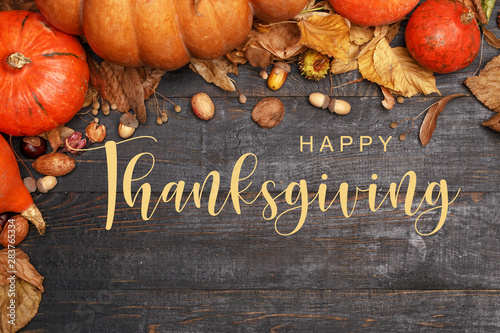 Thanksgiving Greetings. Pumpkins and dry leaves on a dark wooden background. Top view. Flat layer