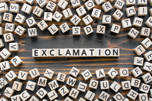 exclamation - word from wooden blocks with letters, express surprise or shock exclamation  concept, random letters around, top view on wooden background