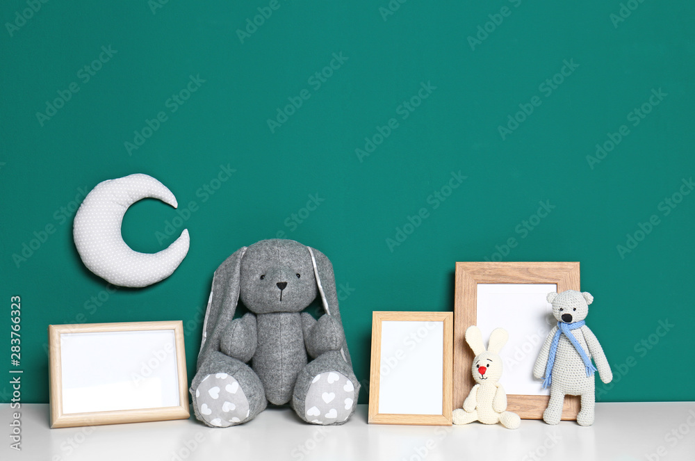 Soft toys and photo frames on table against green background, space for text. Child room interior - obrazy, fototapety, plakaty 