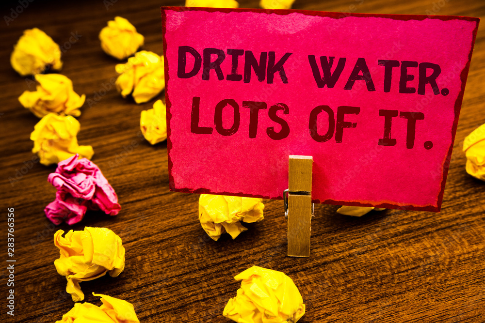 Fototapeta premium Conceptual hand writing showing Drink Water. Lots Of It. Business photo showcasing drinking liquids to keep our body in great status Paperclip retrain pink card with letters wooden floor hunch