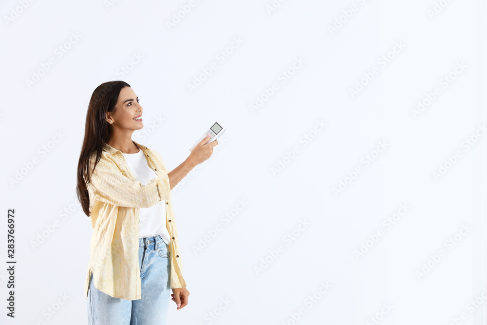 Young woman turning on air conditioner against white background Young woman turning on air conditioner against white background