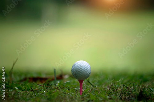 Blurred golf ball on tee in the evening golf course with sunshine in thailand