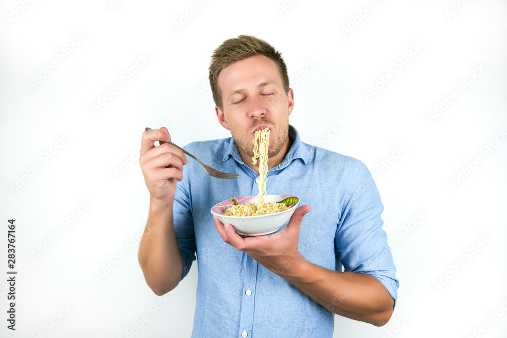 young handsome man eating noodles looks hungry on isolated white background young handsome man eating noodles looks hungry on isolated white background