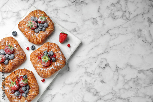 Fotografía Fresh delicious puff pastry with sweet berries on white marble table, top view