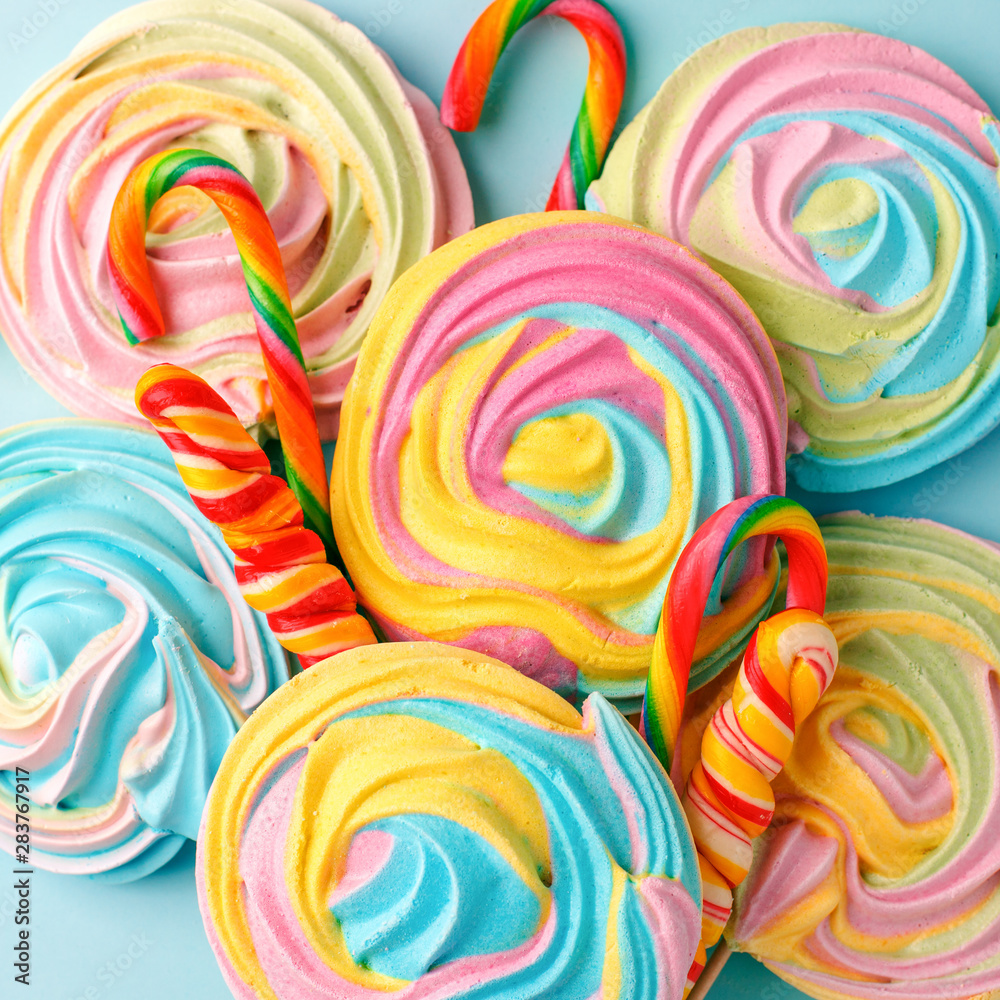 Crispy unicorn rainbow twisted meringue and confectionery lolly pops candies on blue background. Concept love of sweet, birthday party, sugar sweets