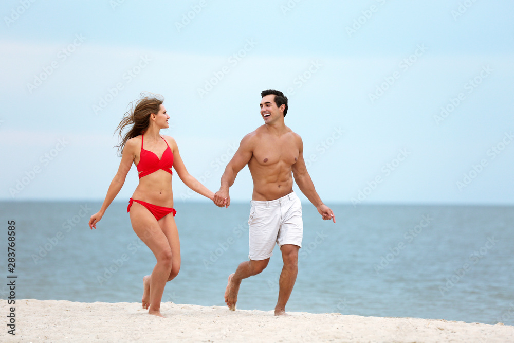 Happy young couple running together on sea beach