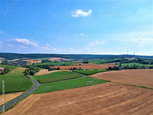 Farmland with fields and country road. Sky and clouds. Photographed from above