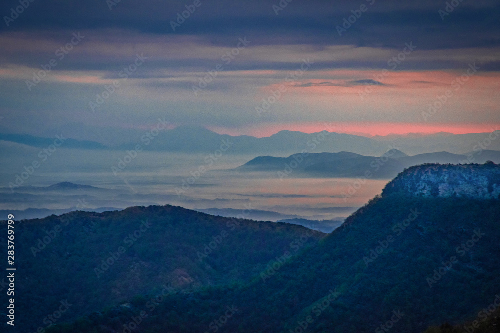 Red light before dawn shines on the valley as seen from the mountain top. Red light before dawn shines on the valley as seen from the mountain top.