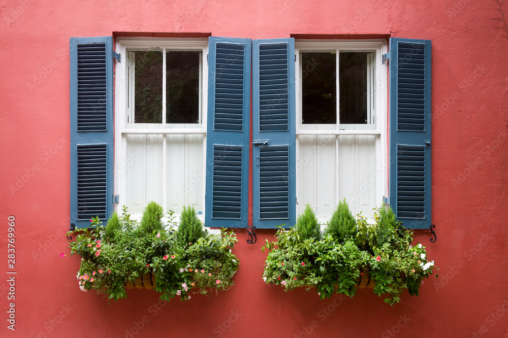 Scenic summer detail of window boxes filled with summer greenery decorating a traditional old Georgian colonial building with blue shutters in Charleston, South Carolina, USA