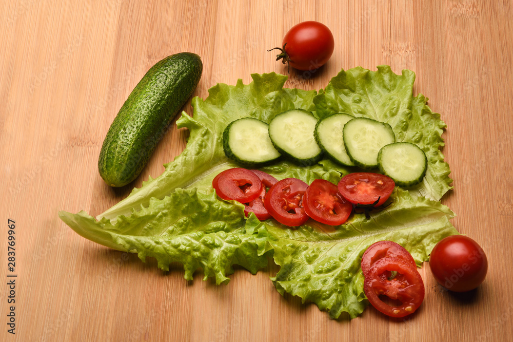 Fresh cucumbers, tomatoes and lettuce on a wooden background. Fresh cucumbers, tomatoes and lettuce on a wooden background.
