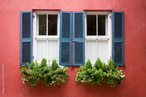 Scenic summer detail of window boxes filled with summer greenery decorating a traditional old Georgian colonial building with blue shutters in Charleston, South Carolina, USA © lazyllama
